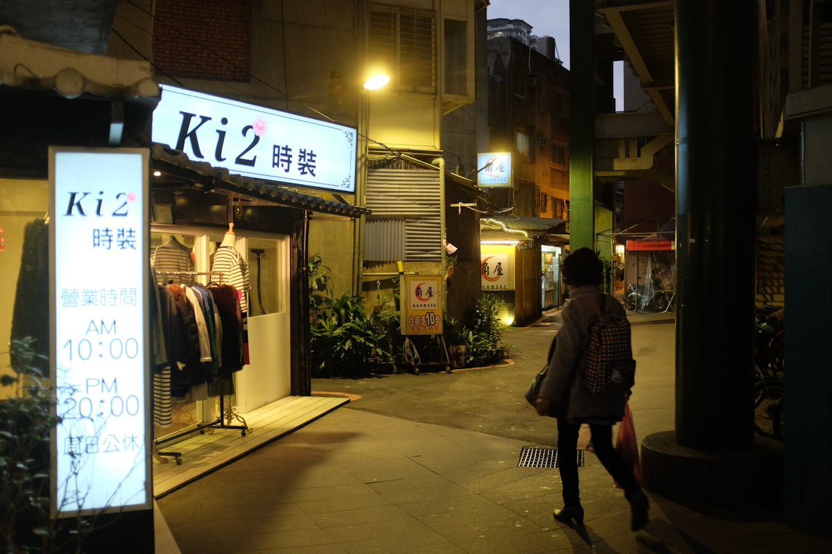 man in black jacket walking on sidewalk during night time