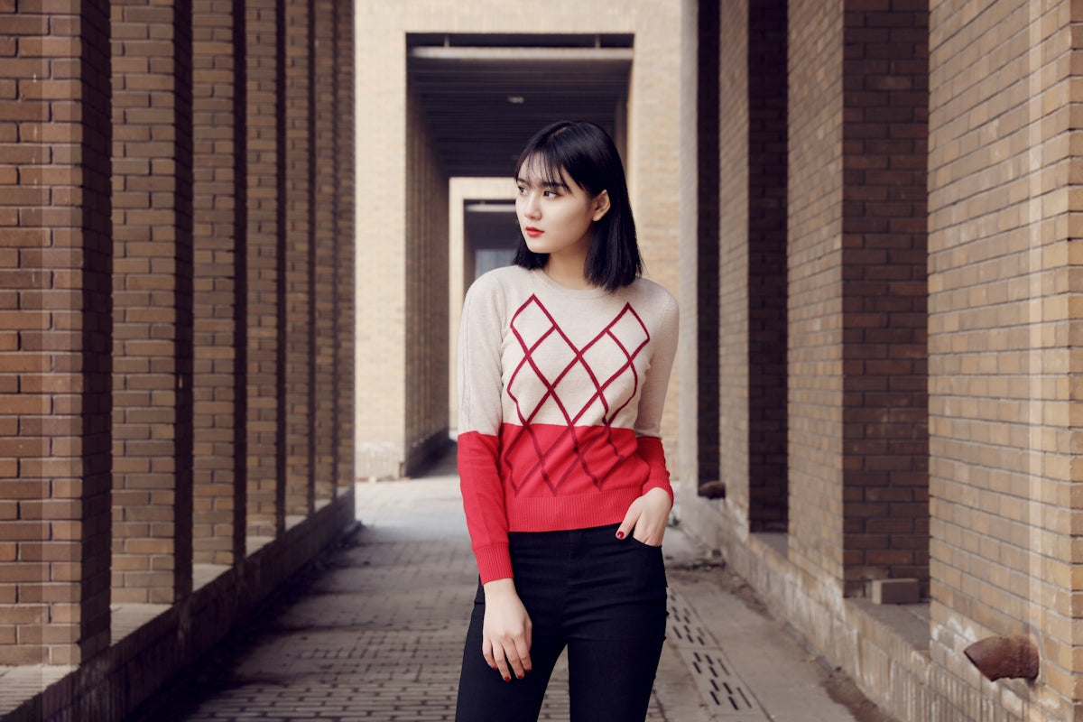 woman in red and white long sleeve shirt and black pants standing on sidewalk during daytime