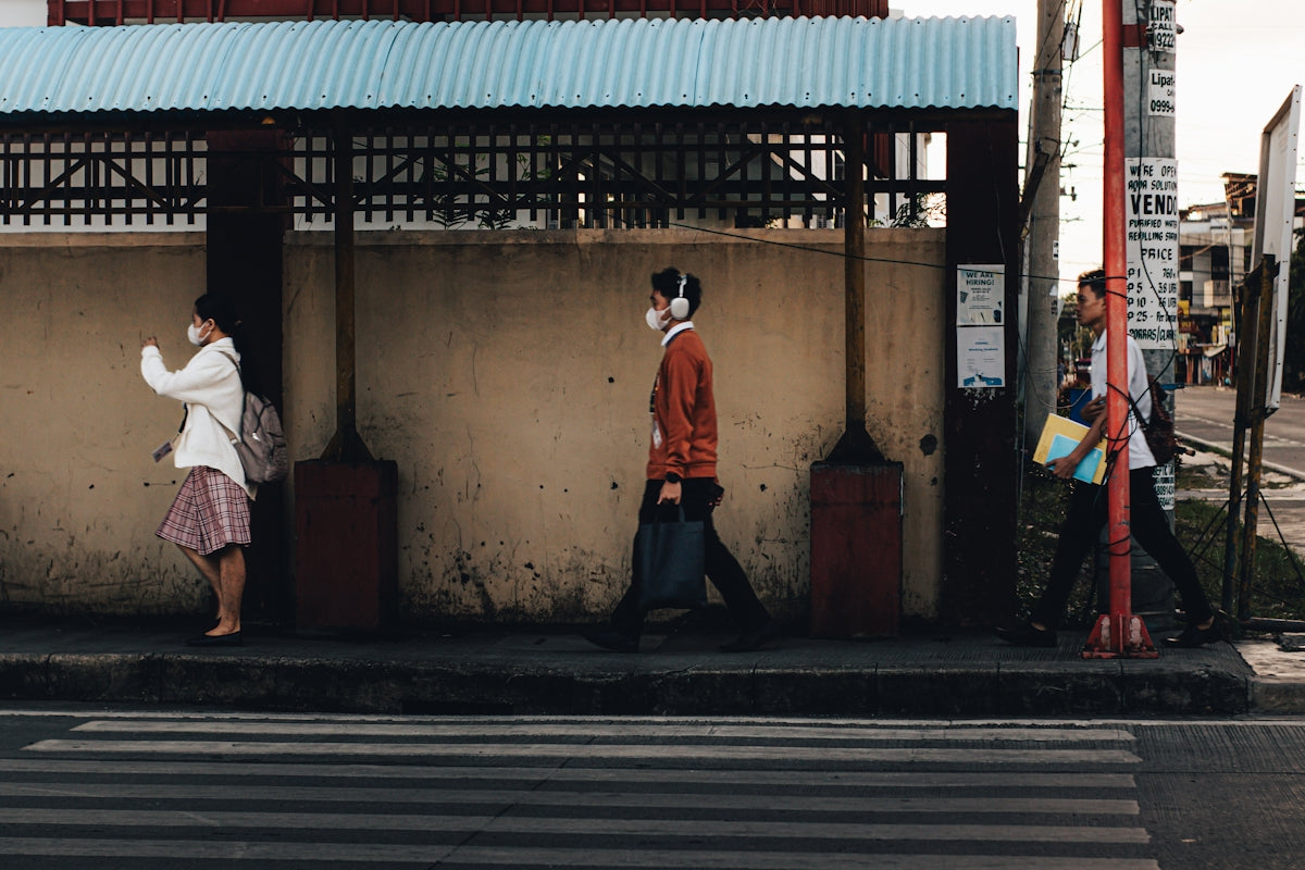 People wear face masks walking on a street.