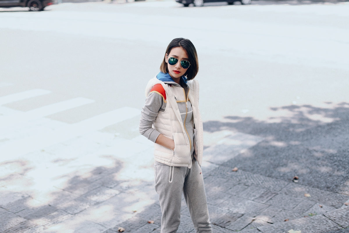 woman in white jacket and gray pants standing on gray concrete pavement during daytime