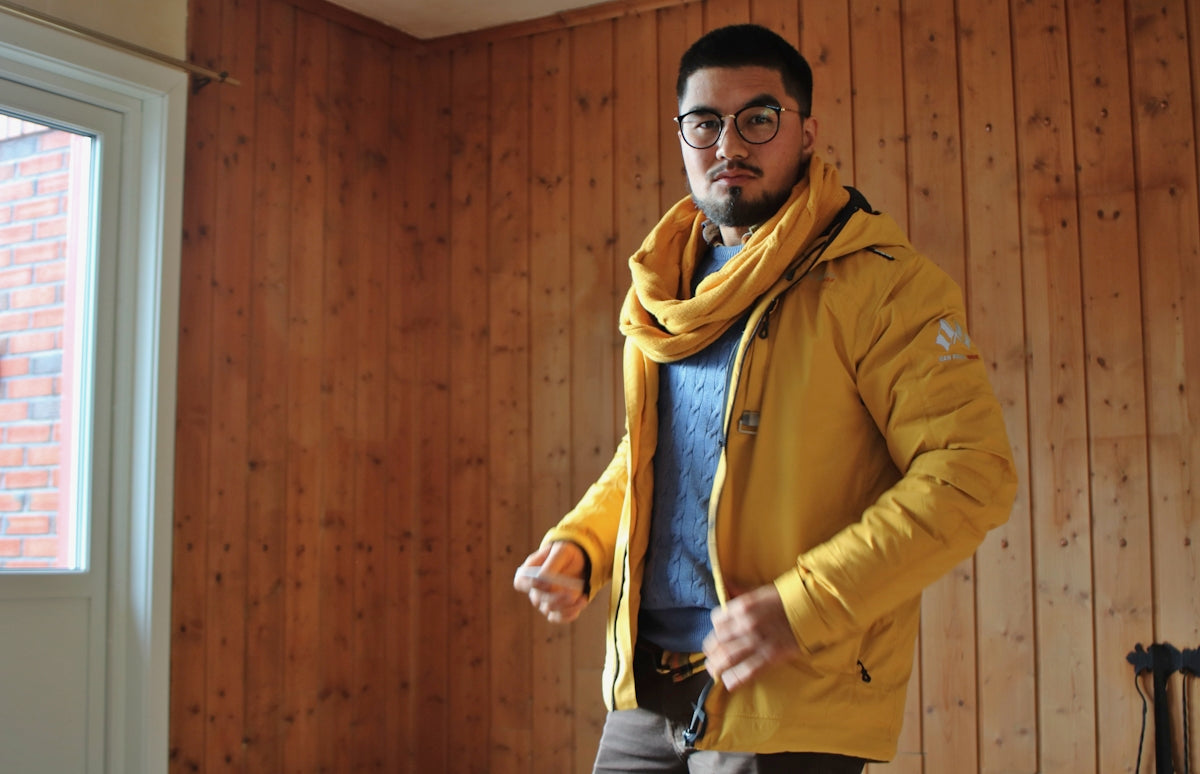 man in yellow jacket wearing yellow scarf and black framed eyeglasses