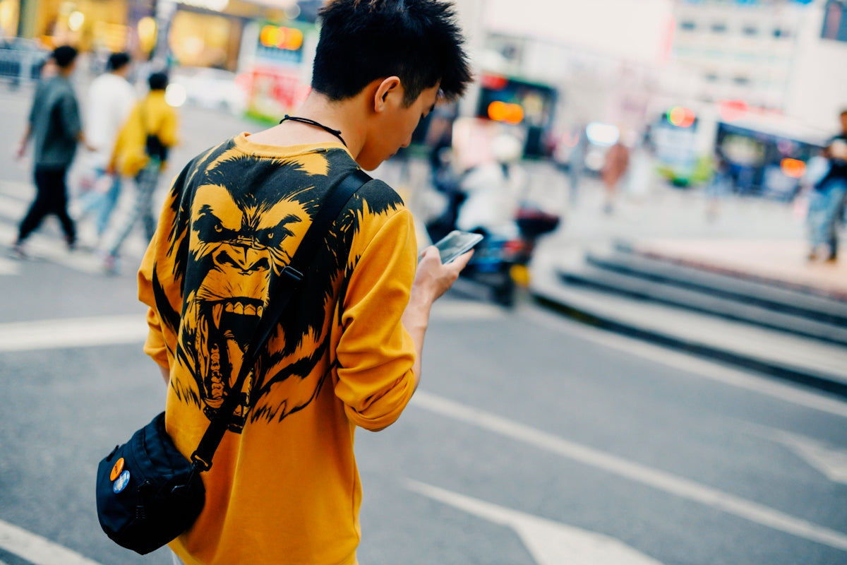 man in yellow black and white jacket holding smartphone