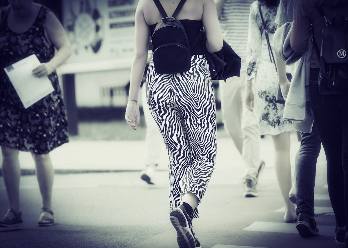 a woman walking down a street with a backpack on her back