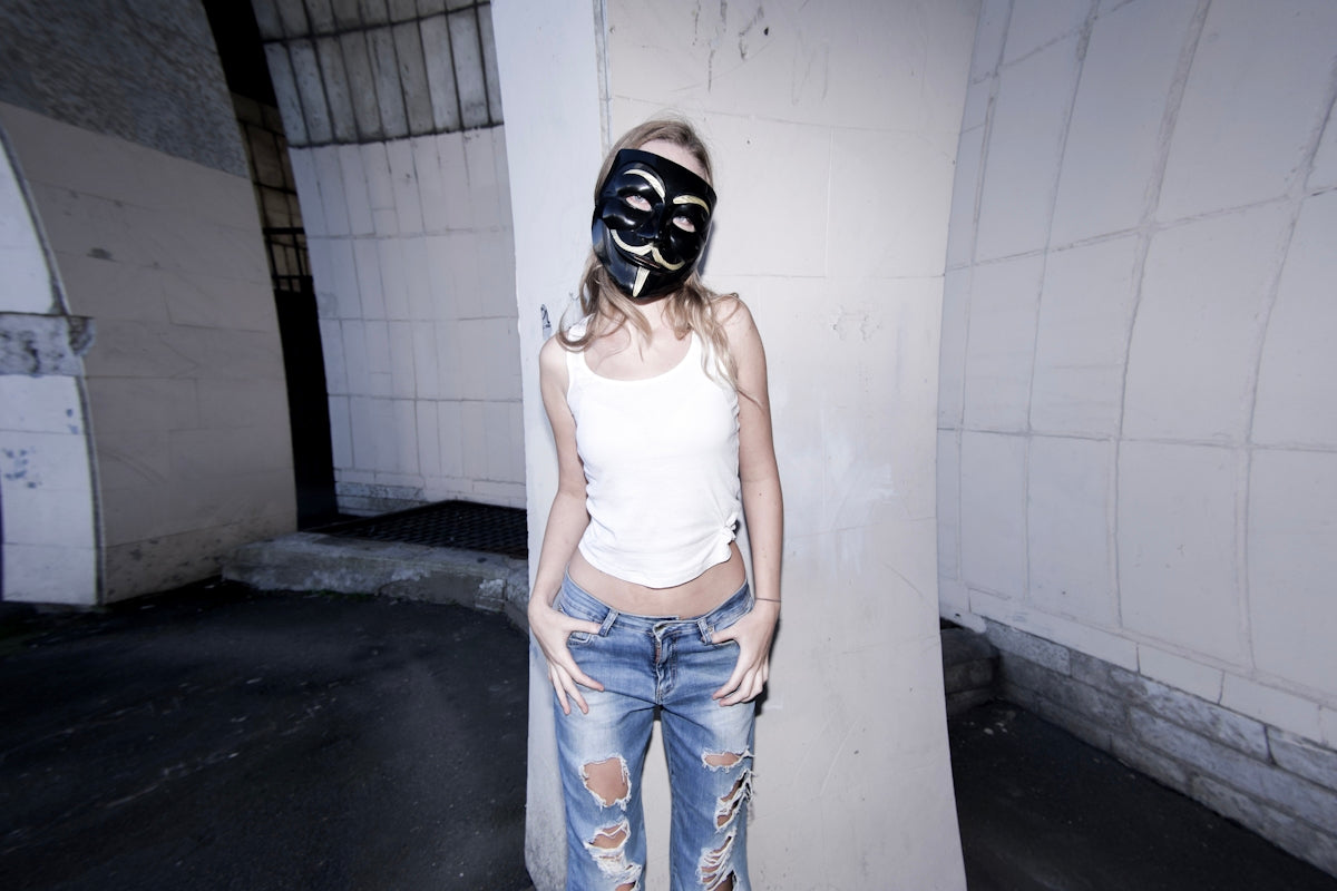 A woman wearing a mask standing next to a wall