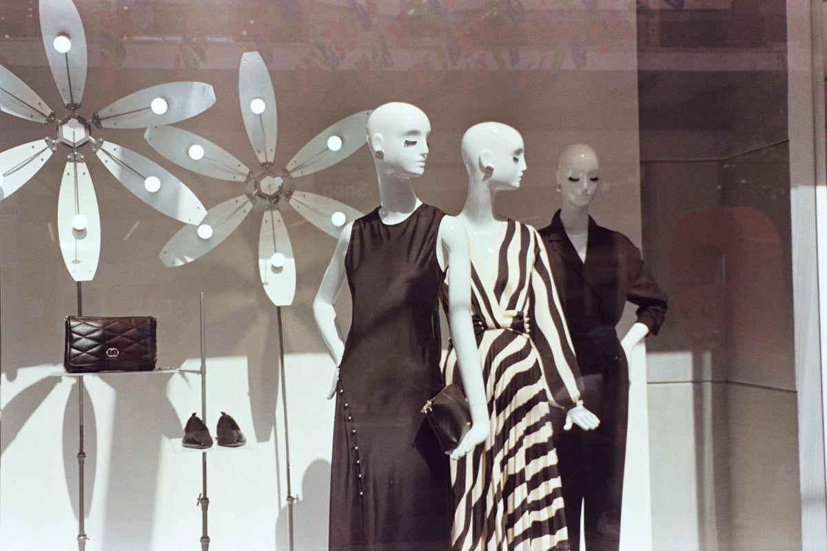 Two mannequins are standing in front of a window